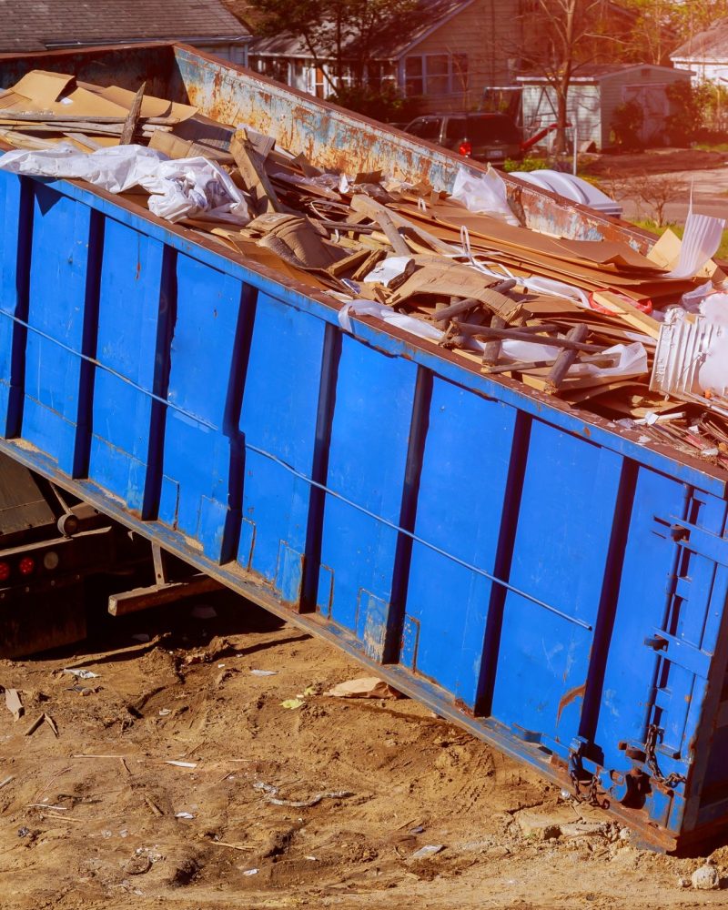 Industrial garbage bin blue construction debris container filled with rock and concrete rubble.