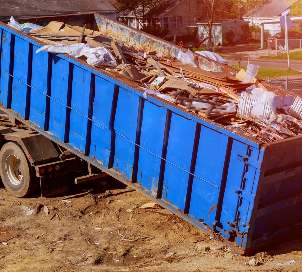 Industrial garbage bin blue construction debris container filled with rock and concrete rubble.